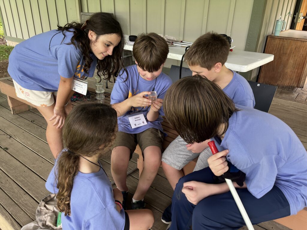 kids in purple shirts clustered around a sample