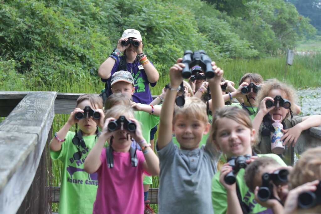 children holding binoculars next to a pond